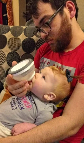 dad feeding baby with breastmilk bottle