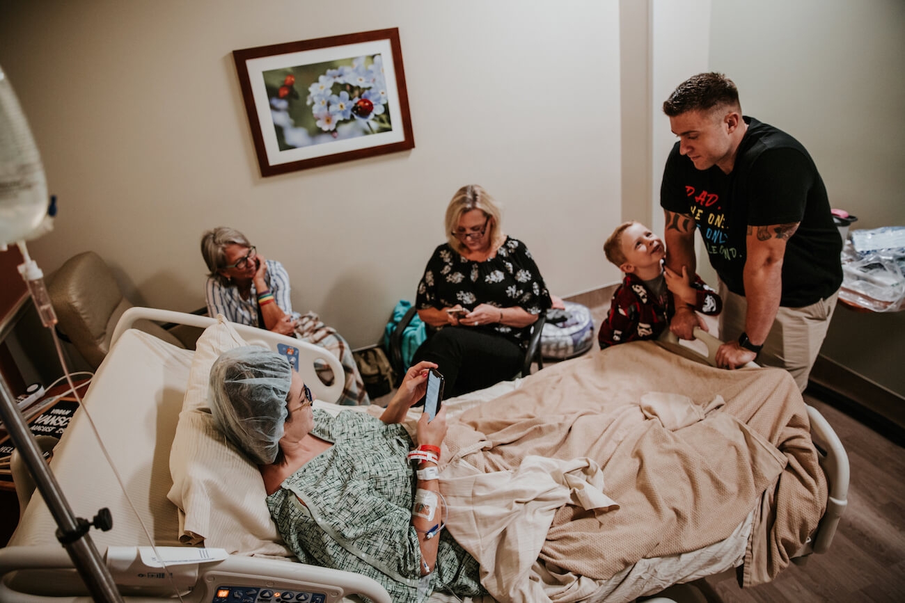 Mother in hospital bed with family