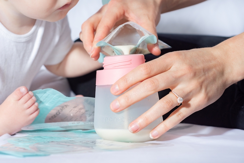 mom pouring milk into bottle from storage bags