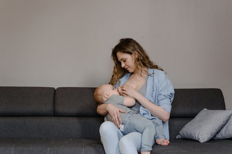 mom breastfeeding baby on couch