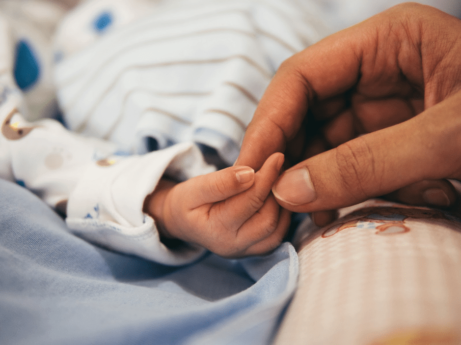 parent holding babys hand in hospital